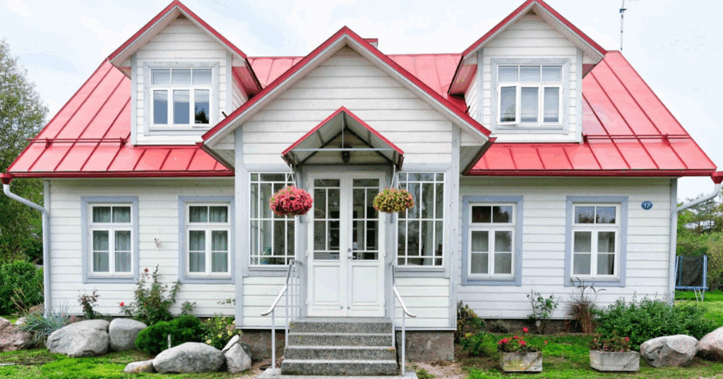 A large home with white siding and a red roof