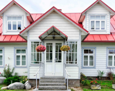 A large home with white siding and a red roof