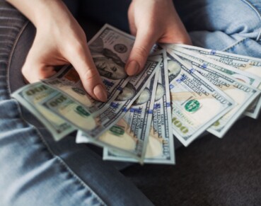 A man holds up many dollar bills in his hands